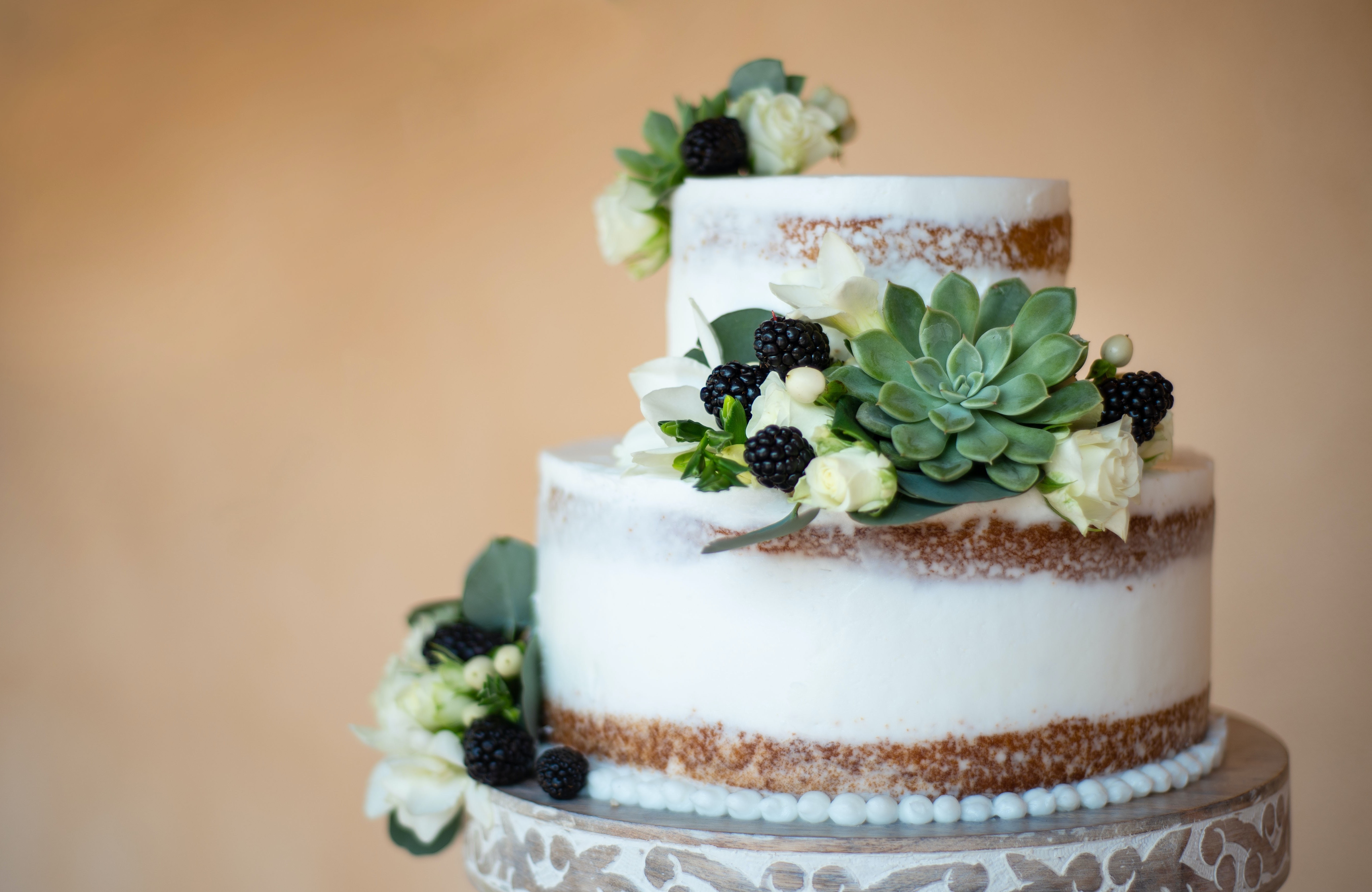 A stunning two-tier brown and white wedding cake adorned with white flowers, succulents, and berries.